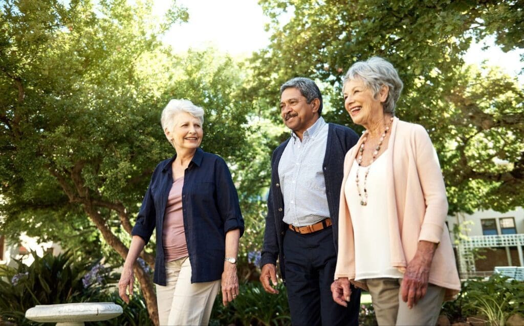 three older adults on a walk outside at their senior living community